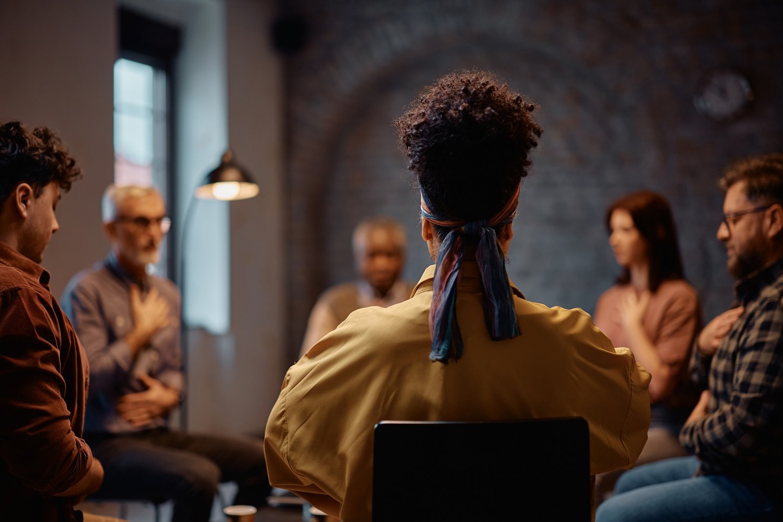 Rear view of a woman during group therapy at mental health center.
